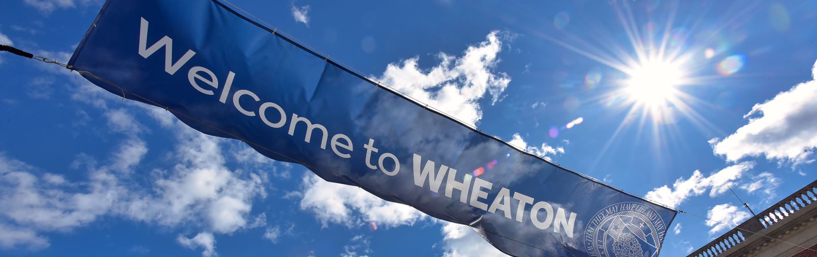 Banner that reads, "Welcome to Wheaton" across a blue sky with clouds