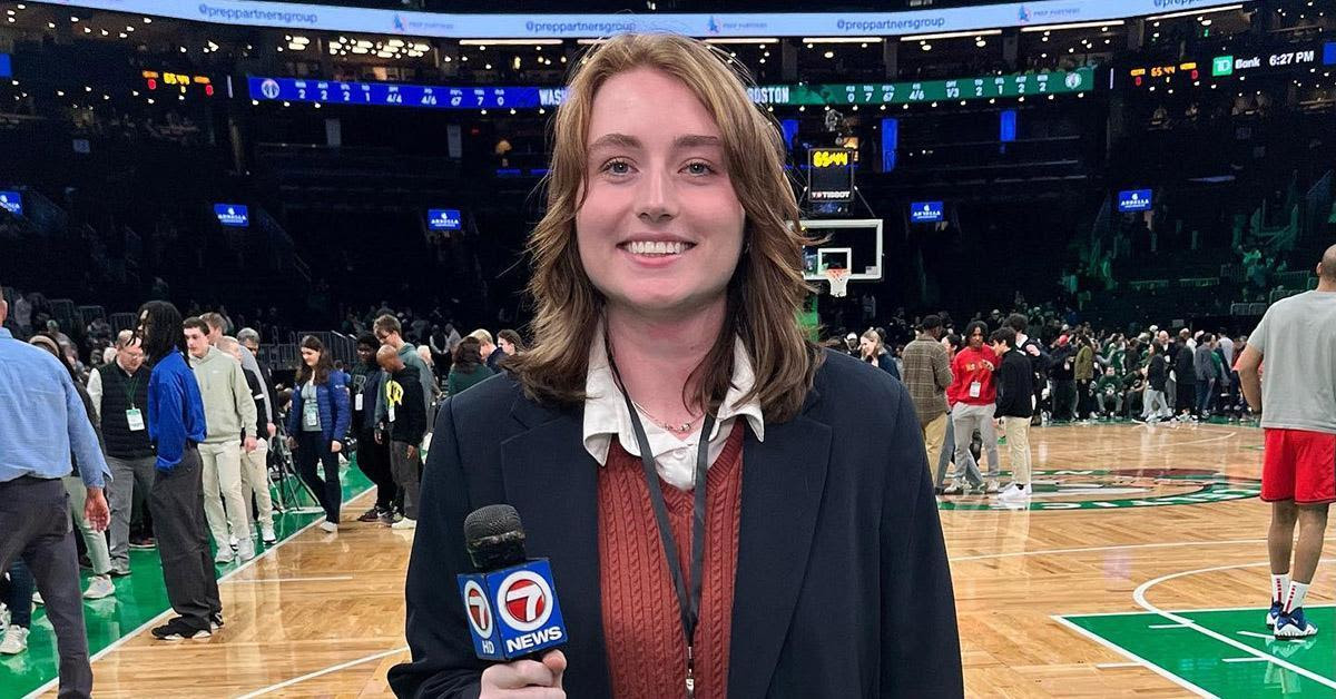 A young woman is holding a microphone on a basketball court